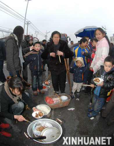 京珠高速公路湖南湘潭馬家河收費站滯留的旅客就地購買商販的食物（1月27日攝）。