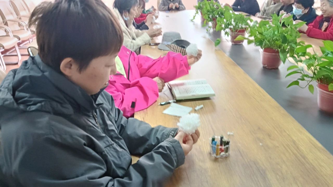 活动现场,社区工作人员为居民演示了折纸花的方法,现场居民看着